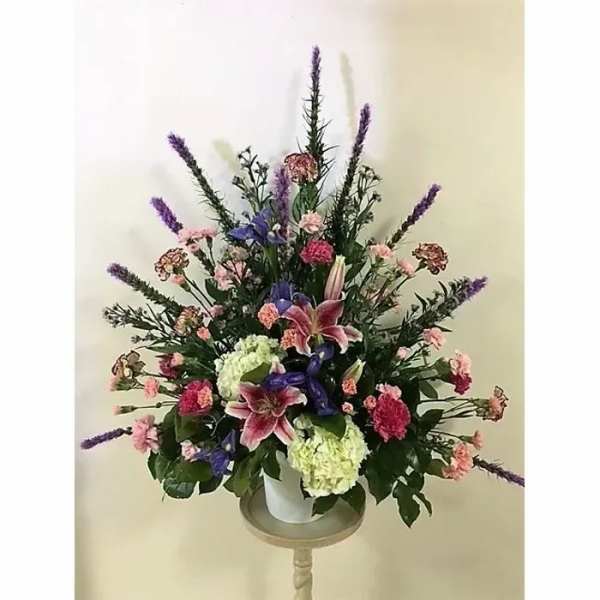 Tall mixed floral arrangement in a white container with pink and purple blooms