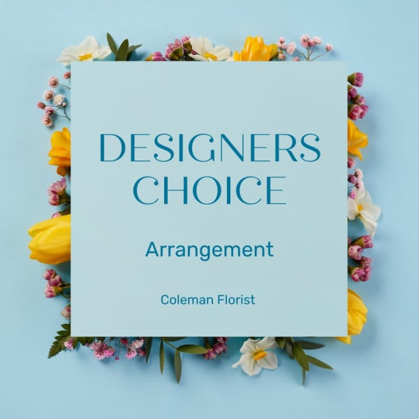 Floral arrangement around a blue card reading Designers Choice Arrangement