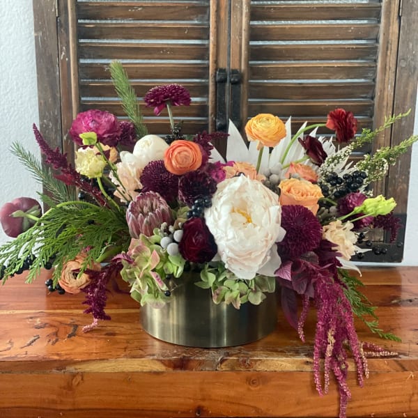 Mixed bouquet of pink, peach, white, and burgundy flowers in a metal vase