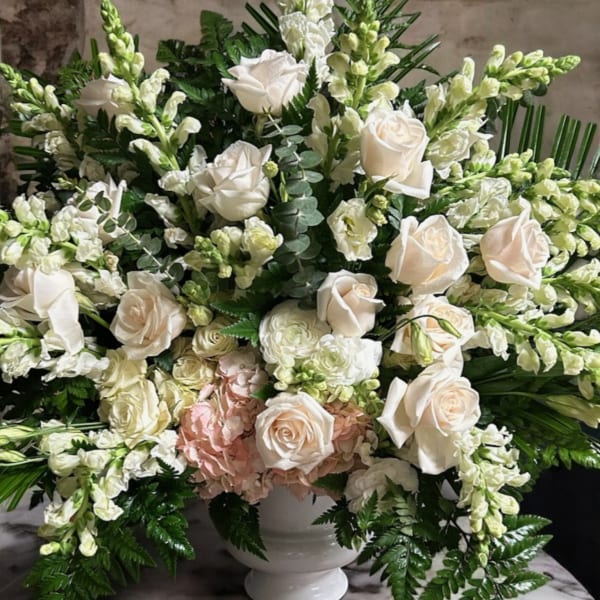 White roses and pale blooms arranged in a white urn