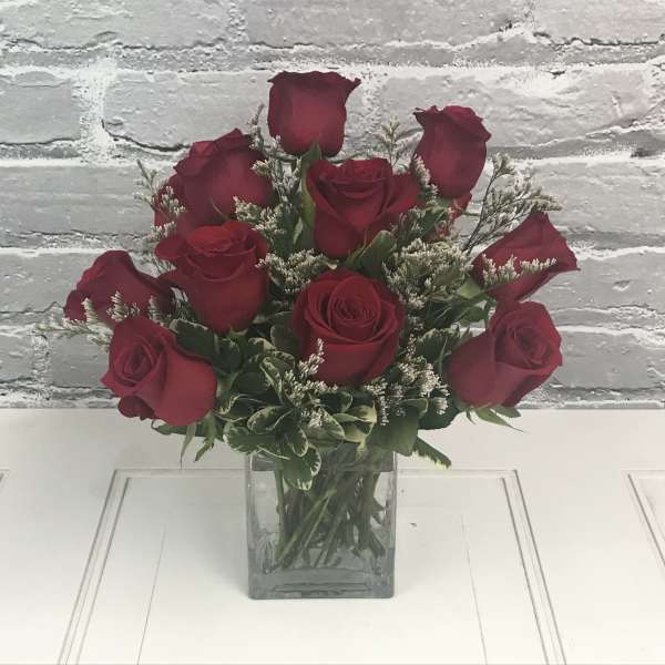 Red roses arranged in a clear square glass vase