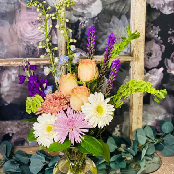 Mixed bouquet in a clear glass vase with roses and daisies