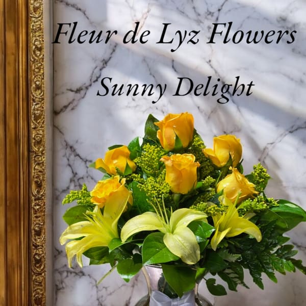 Yellow roses and lilies arranged in a glass vase with a ribbon