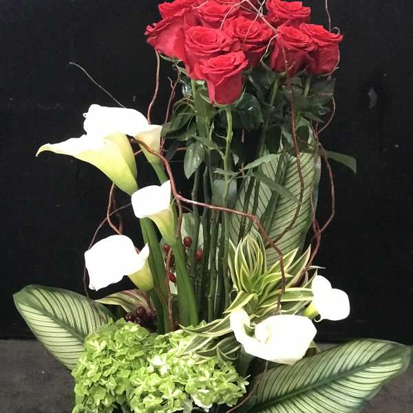 Tall arrangement of red roses and white calla lilies with green hydrangea