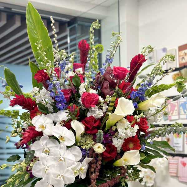 Large mixed bouquet with white orchids, red roses, and calla lilies in a vase