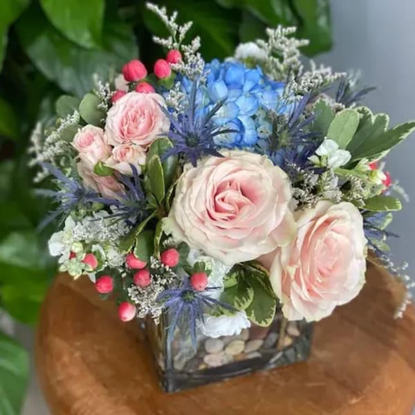 Pink roses and blue hydrangea in a square glass vase