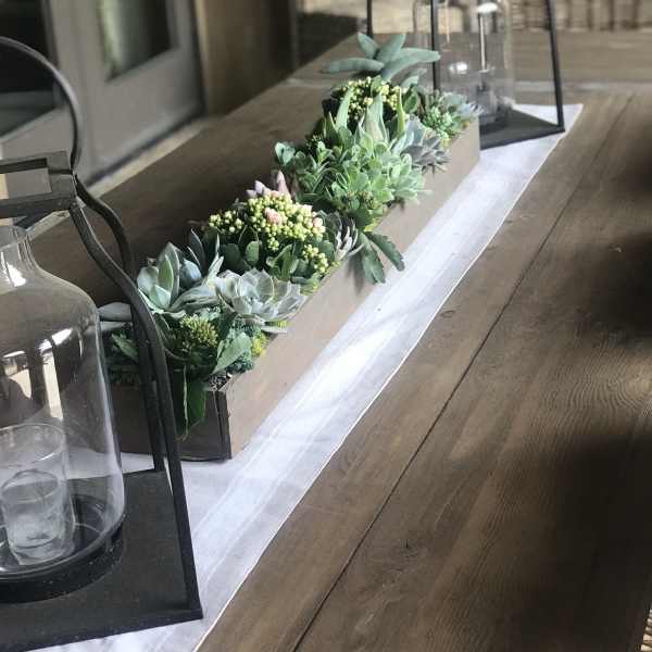 Succulent centerpiece in a long rectangular box with lanterns on a table