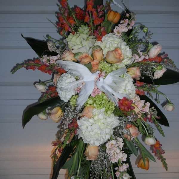 Large standing floral spray with white doves and peach, white, and orange flowers