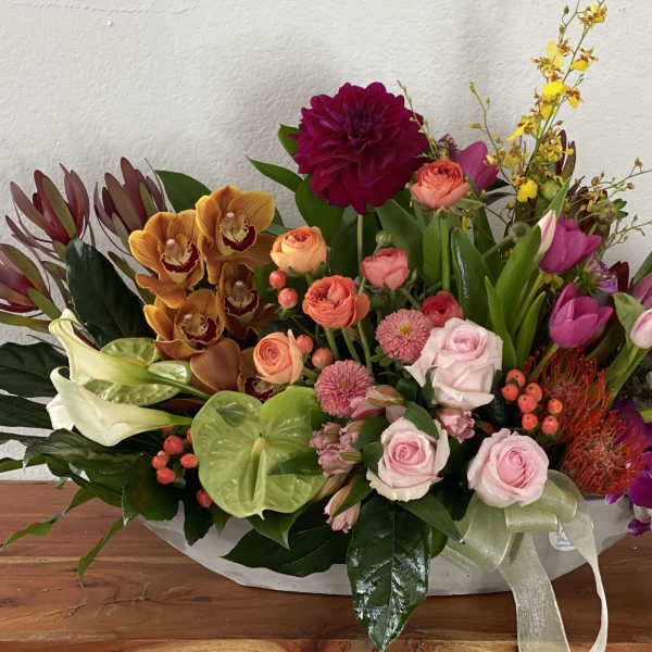 Colorful mixed flower arrangement in a low white container