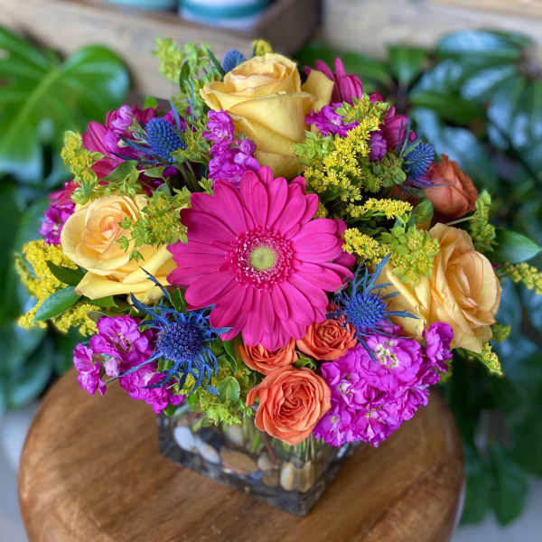 Colorful mixed bouquet in a square glass vase with roses and a gerbera daisy