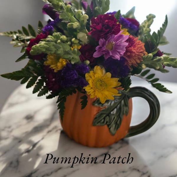 Mixed flowers arranged in a pumpkin-shaped mug
