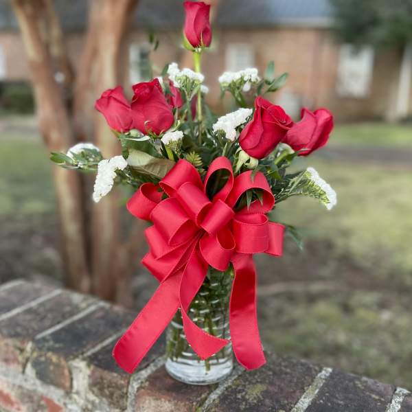 Red roses in a glass vase with a large red ribbon bow