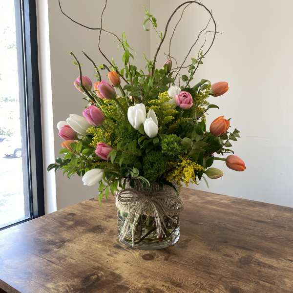 Tulip arrangement in a glass vase with curly branches