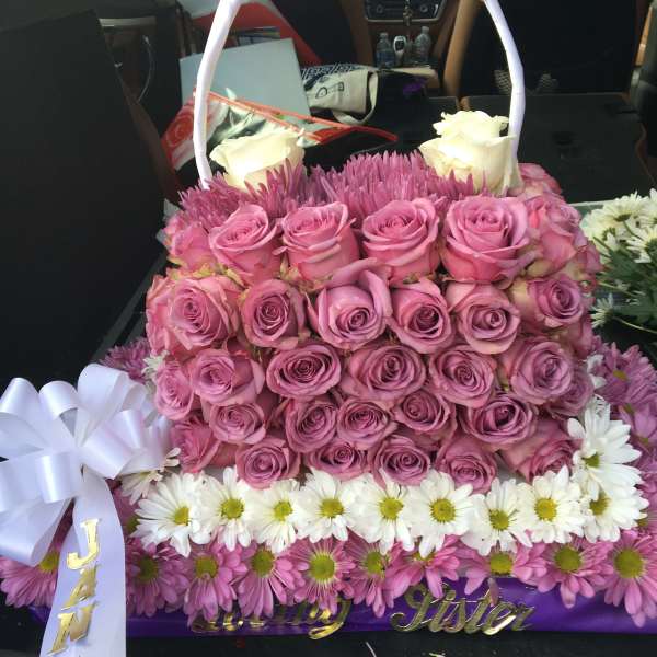 Basket arrangement of pink roses, white roses, and daisies