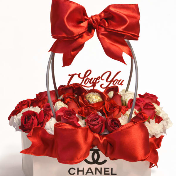 Red roses and white flowers in a gift box with a large red bow