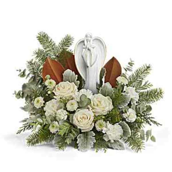 White roses arranged around an angel figurine with evergreen accents