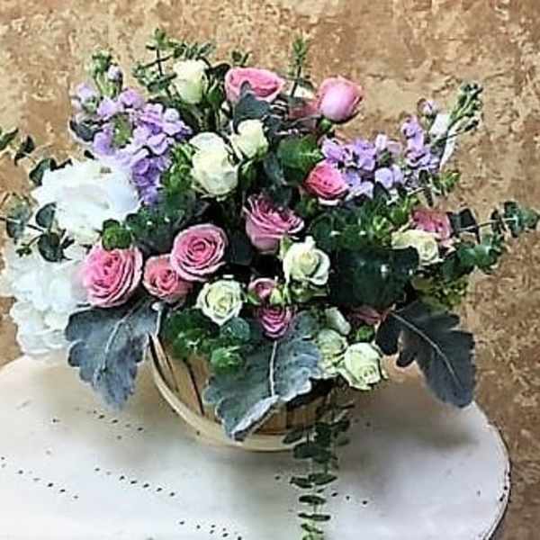 Bouquet of pink and white roses with lavender flowers in a round container