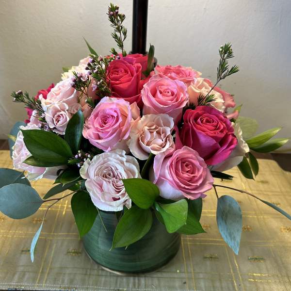 Pink and blush roses arranged in a low green vase