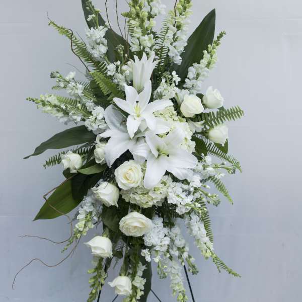 White lilies and roses in a tall standing floral arrangement