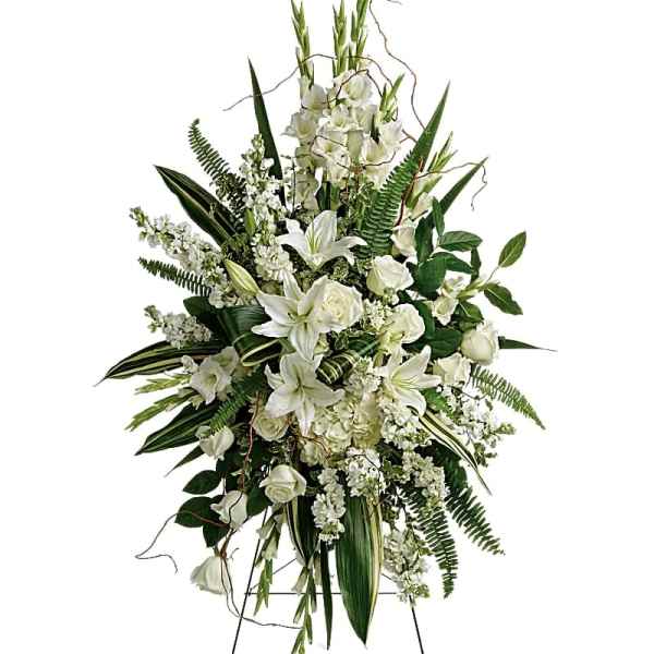 White funeral spray with lilies, roses, and greenery on an easel