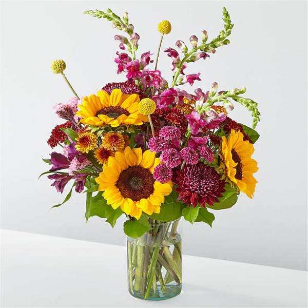 Bouquet of sunflowers and mixed pink flowers in a glass vase