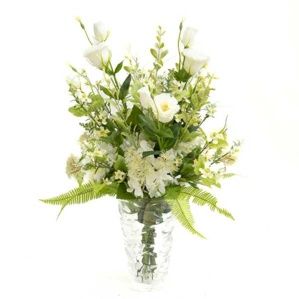 White floral arrangement in a clear glass vase with fern accents