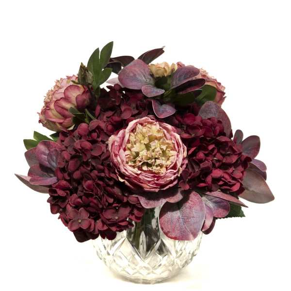 Pink and burgundy floral arrangement in a cut glass vase