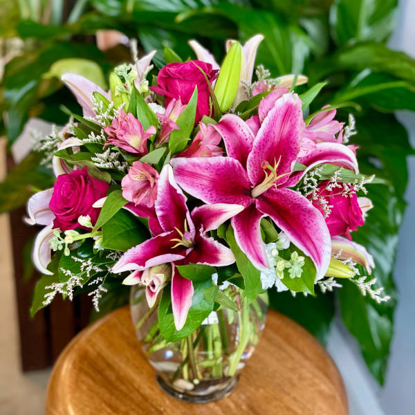 Pink lilies and roses arranged in a clear glass vase
