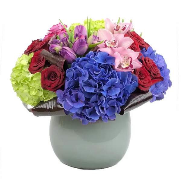 Colorful bouquet of hydrangeas, roses, and orchids in a gray vase