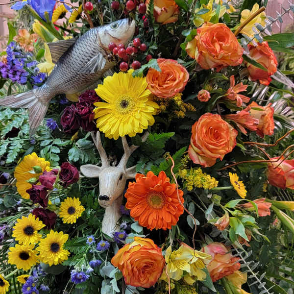 Large mixed flower arrangement with a fish and deer decoration