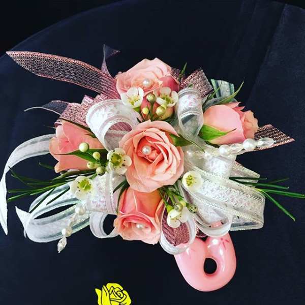 Pink rose corsage with white ribbon and pearl accents