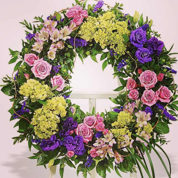 Circular floral wreath with pink roses, purple blooms, and yellow hydrangeas