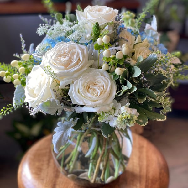 White rose bouquet in a glass vase with blue accents