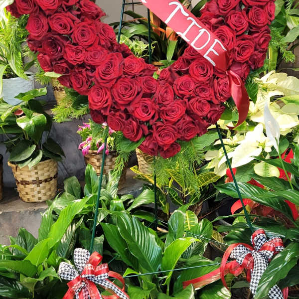 Heart-shaped red rose wreath with a pink ribbon sash