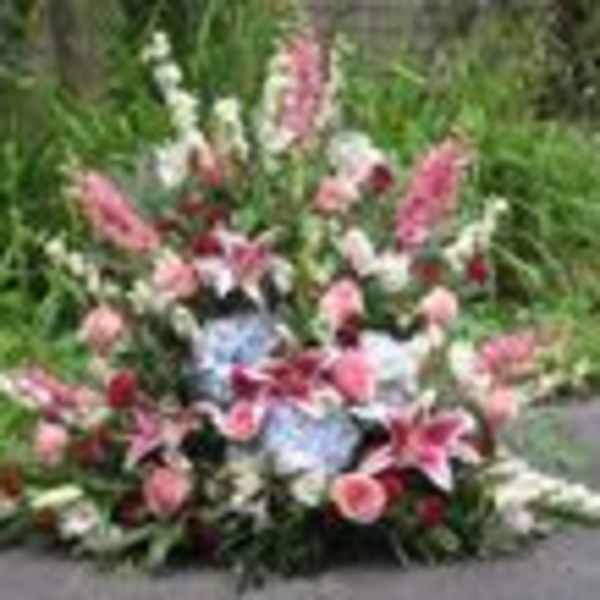 Large outdoor flower arrangement with pink lilies and mixed blooms