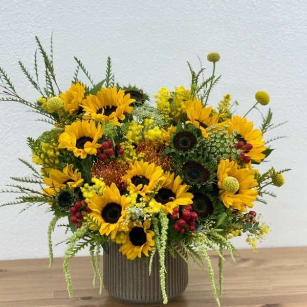 Sunflower arrangement in a ribbed vase with yellow and red accents