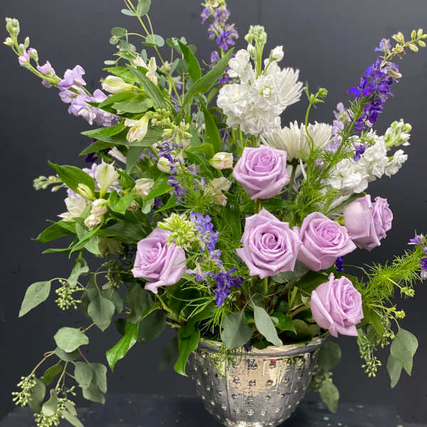 Lavender roses and white flowers in a silver pedestal vase