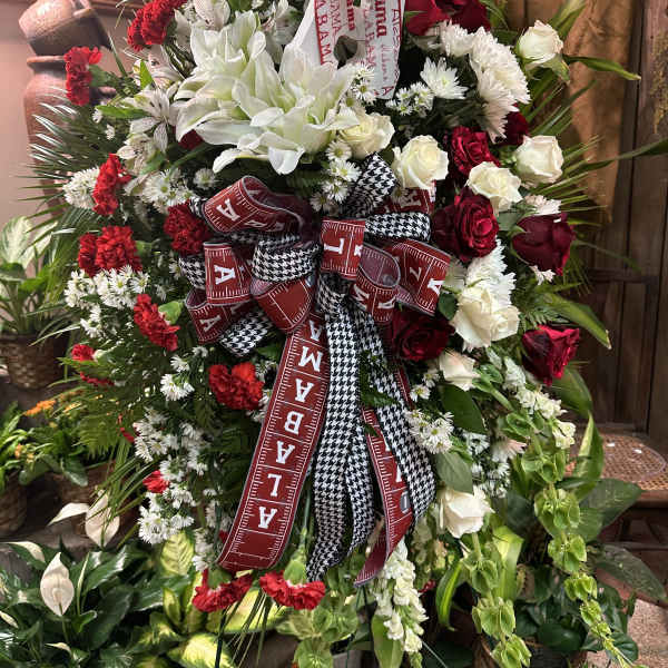 Large red, white, and black floral standing spray with ribbons and a houndstooth hat
