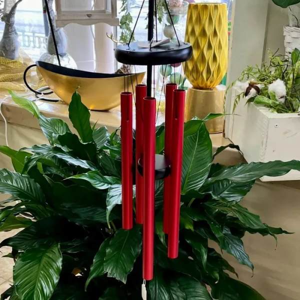Red wind chimes above a lush green potted plant arrangement