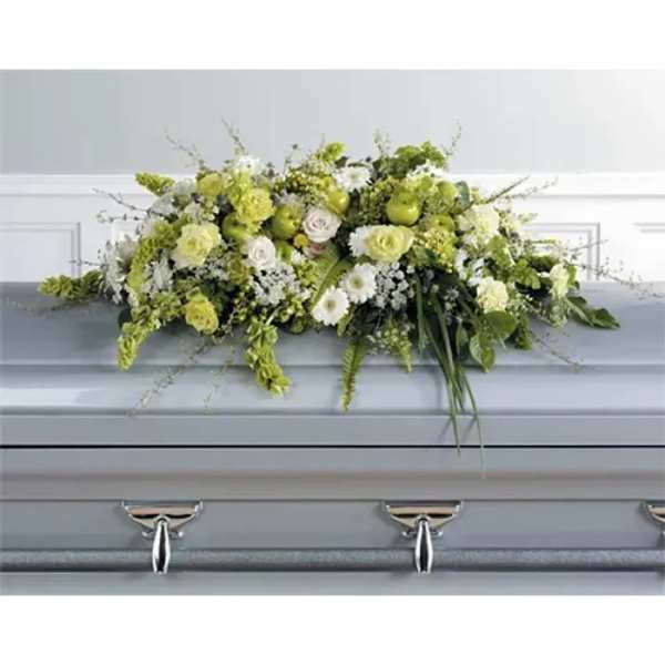 Green and white floral casket spray on a gray casket