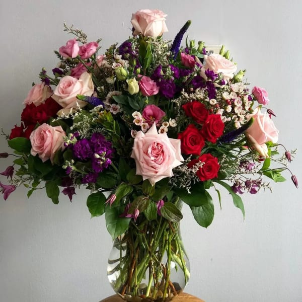 Large bouquet of pink, red, and purple flowers in a clear glass vase