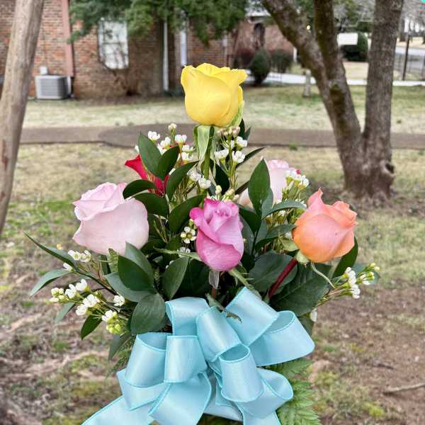 Bouquet of multicolored roses in a glass vase with a blue ribbon
