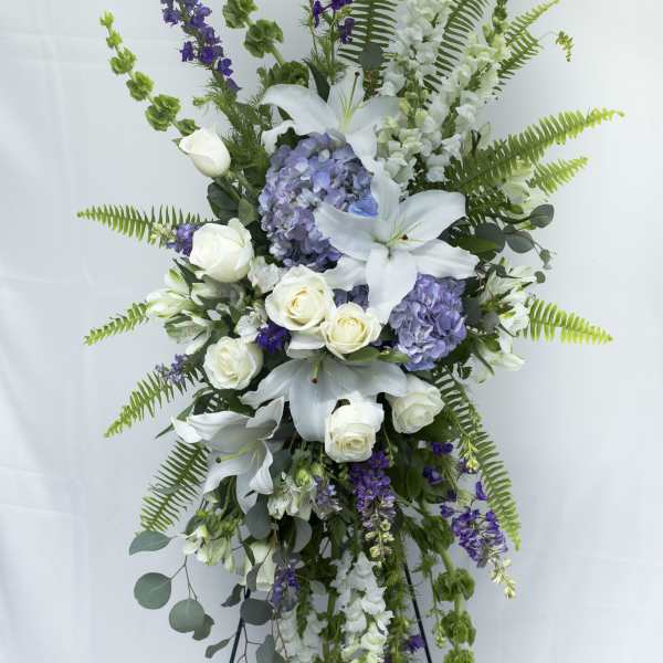 Tall standing floral spray with white lilies, roses, and purple blooms