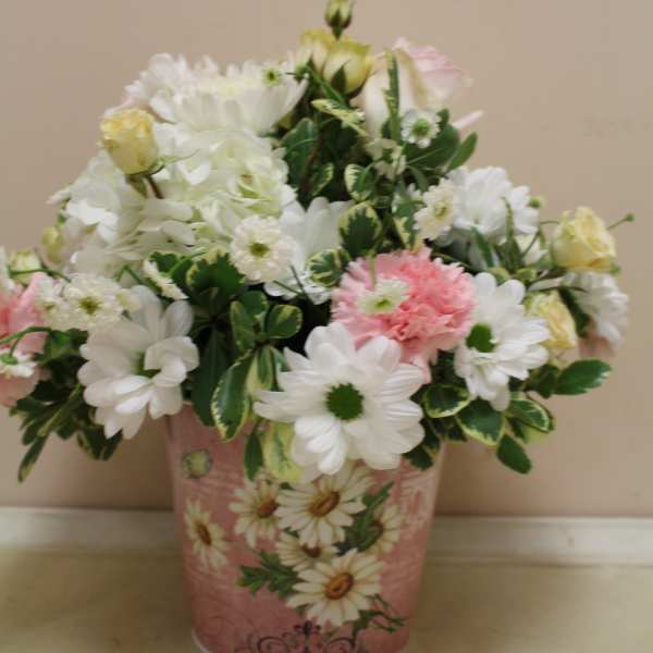 Pink and white flower arrangement in a decorative tin container