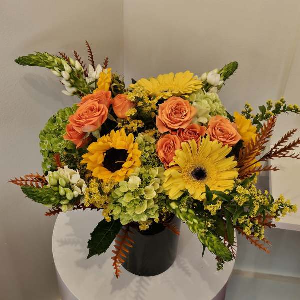 Orange roses and yellow gerbera daisies in a black vase