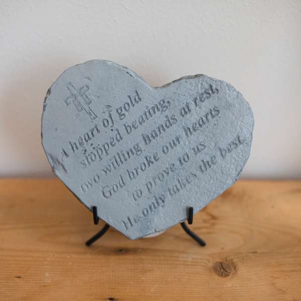 Heart-shaped stone plaque with engraved religious text on a stand