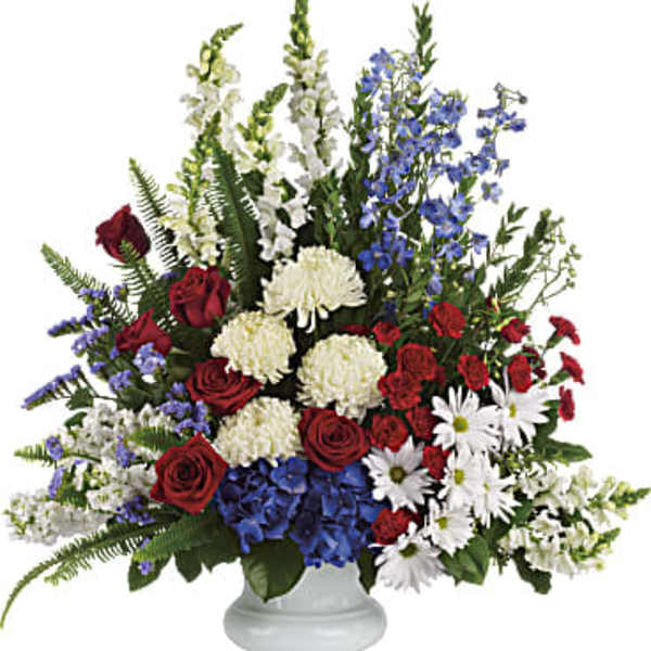 Large mixed flower arrangement in a white pedestal vase