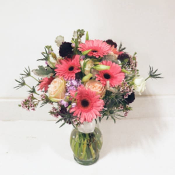 Pink gerbera and peach roses in a glass vase