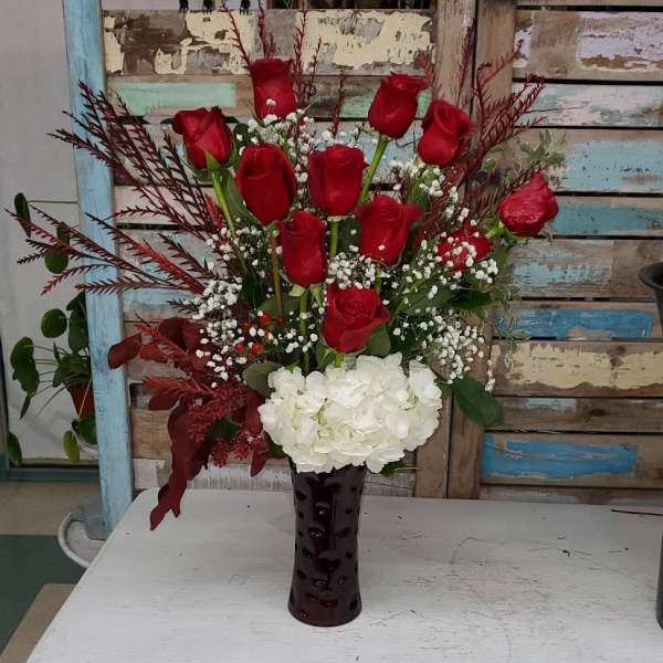 Red roses and white hydrangea in a dark vase