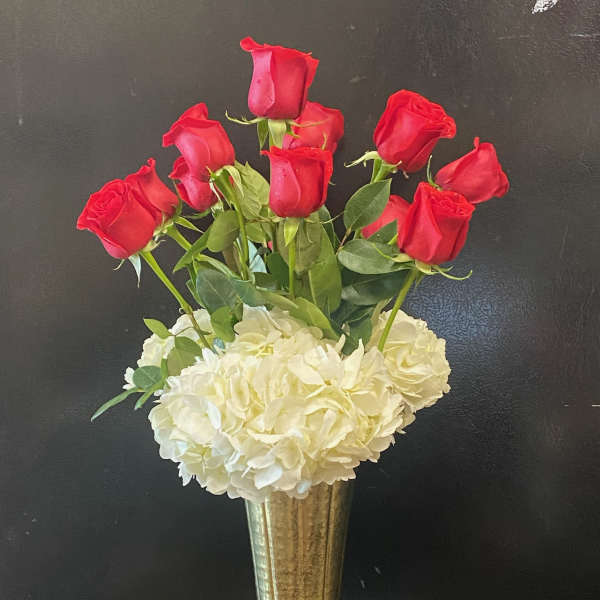 Red roses above white hydrangeas in a gold vase